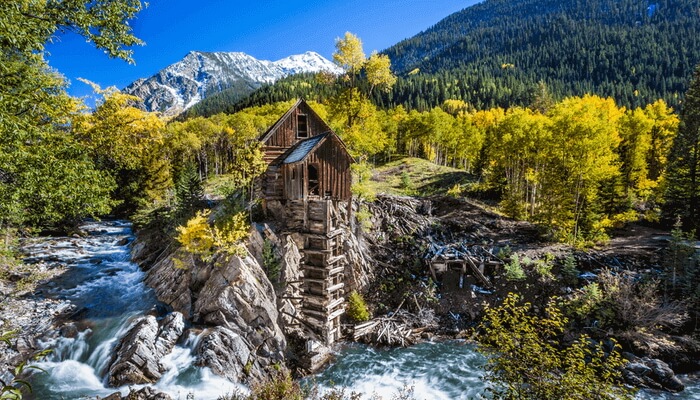 Image of Crystal Mill in Marble, Colorado. The old wooden mill is rustic and has a sense of history as it is nestled amoung the forest and running river below.