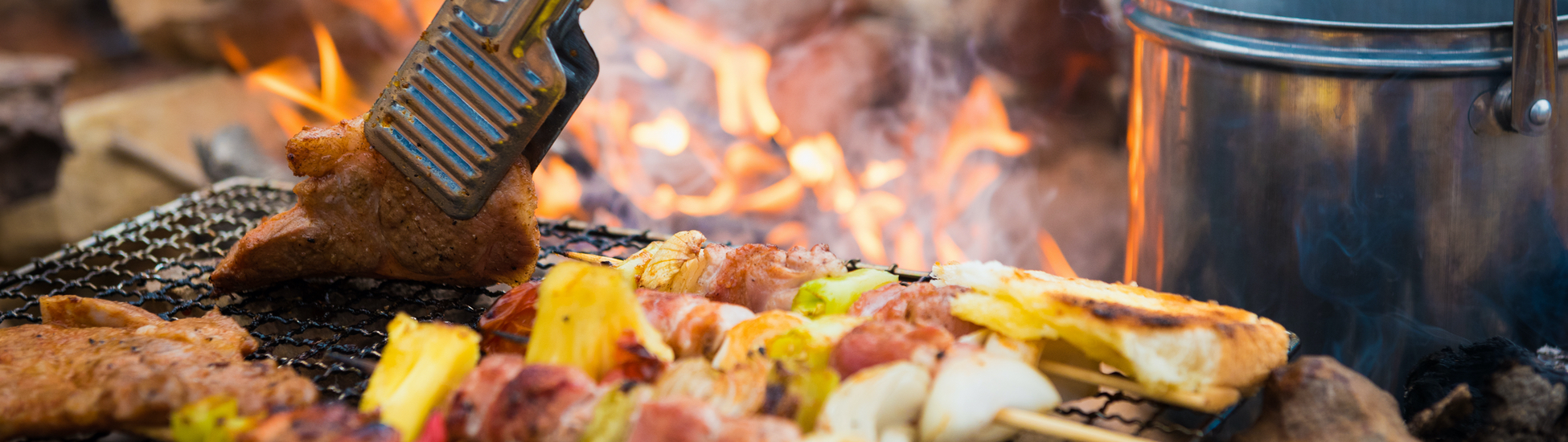 Image of kabobs and chicken grilling on the campfire