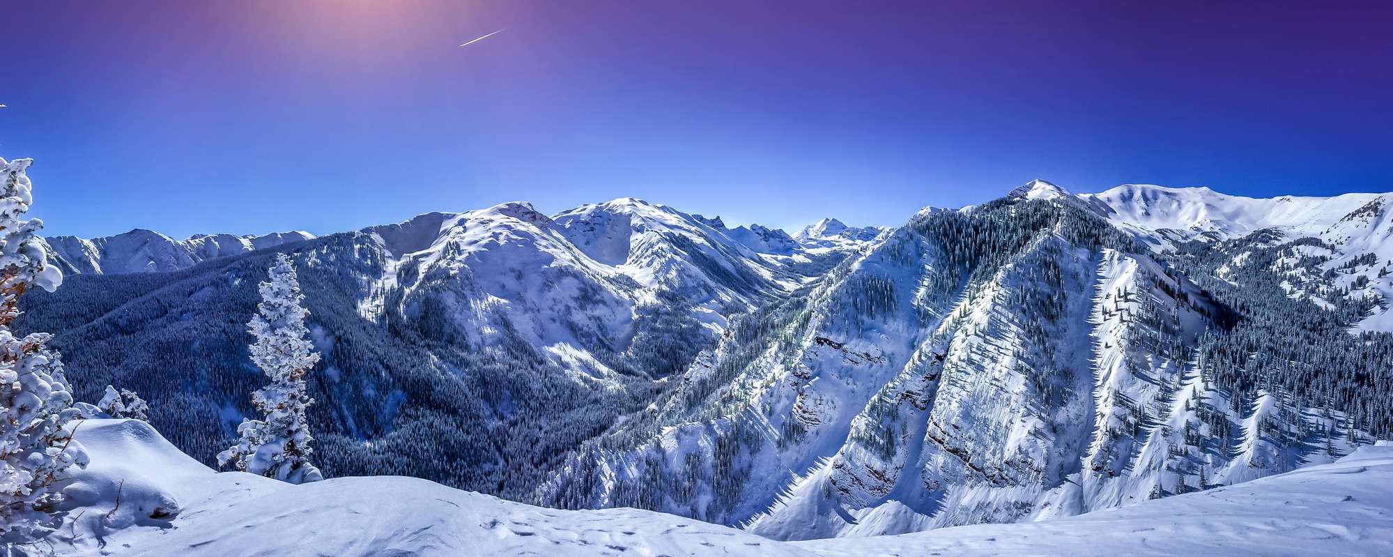 Image of snow covered mountains and a bright blue sky - winter season